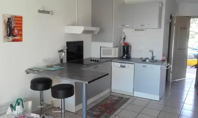 a kitchen with a sink and a counter with stools at Haute Corse. Studio 4 pers .Plage Piscine. Cervione Prunete . in Cervione