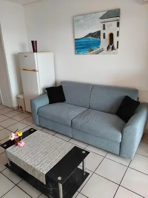 a living room with a blue couch and a coffee table at Haute Corse. Studio 4 pers .Plage Piscine. Cervione Prunete . in Cervione