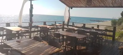 a row of tables and chairs on a deck next to the ocean at Haute Corse. Studio 4 pers .Plage Piscine. Cervione Prunete . in Cervione