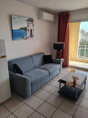 a living room with a blue couch and a table at Haute Corse. Studio 4 pers .Plage Piscine. Cervione Prunete . in Cervione