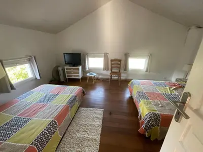 a bedroom with two beds and a tv and two windows at Maison de charme entre mer et montagne in Forciolo