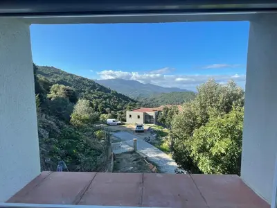 a view from a window of a house with a mountain at Maison de charme entre mer et montagne in Forciolo
