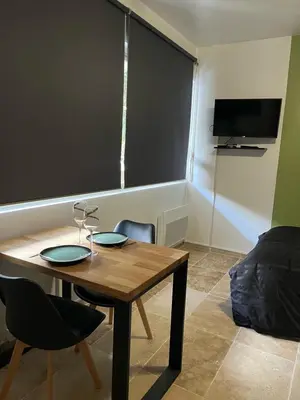 a room with a table and chairs and a tv at Appartement douillet en ville in Ajaccio