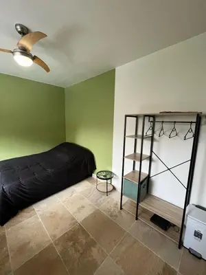 a bedroom with a black bed and a shelf at Appartement douillet en ville in Ajaccio