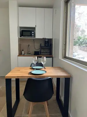 a kitchen with a wooden table with two wine glasses at Appartement douillet en ville in Ajaccio