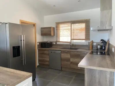 a kitchen with a stainless steel refrigerator and wooden cabinets at Villa avec piscine 3 étoiles proche plages in Monacia-dʼAullène