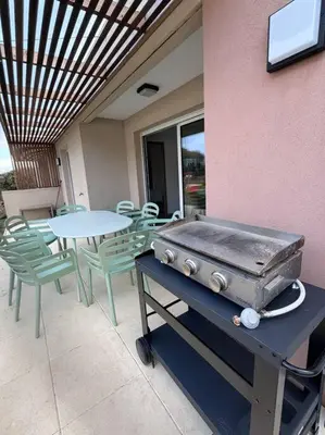 a grill on a table next to a table and chairs at Maison Joepolly corsica in Bonifacio