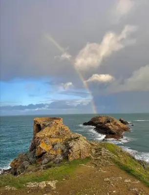 a rainbow in the sky over the ocean with rocks at CASA DI SIGNARE in Ventiseri