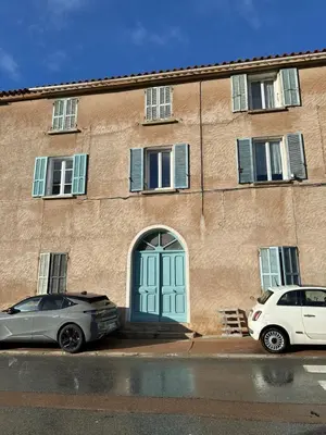 two cars parked in front of a building with a blue door at Appartement Orenaggio in Bonifacio