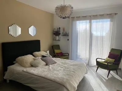 a bedroom with a bed and two chairs and a chandelier at 1,2,3 soleil in Porticcio