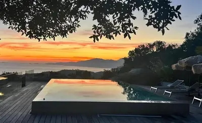 a swimming pool with a sunset in the background at 1,2,3 soleil in Porticcio