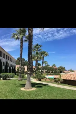 two palm trees in a park near a building at Appartement dans résidence in Linguizzetta