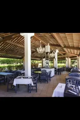 a restaurant with tables and chairs under a roof at Appartement dans résidence in Linguizzetta