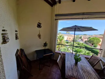 a dining room with a table and an umbrella at Appartement dans résidence in Linguizzetta