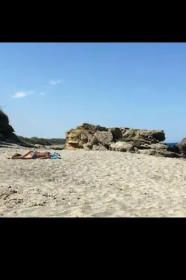 a beach with people laying on the sand at Appartement dans résidence in Linguizzetta