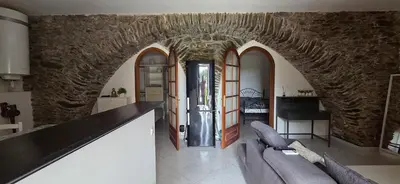 a living room with a couch and a stone wall at Charmante Maison de village, Proche Aéroport in Lucciana