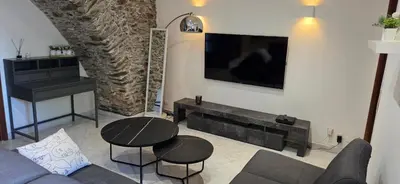 a living room with a couch and a tv on a wall at Charmante Maison de village, Proche Aéroport in Lucciana