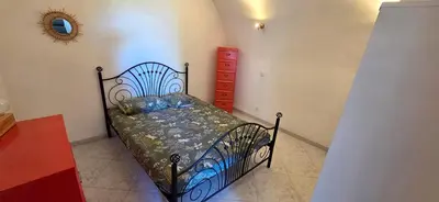 a bedroom with a black bed and a red dresser at Charmante Maison de village, Proche Aéroport in Lucciana