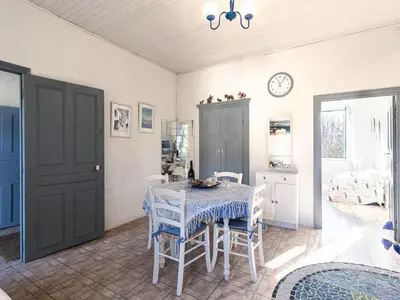 a dining room with a table and chairs and a clock at Apartment Santa by Interhome in Porto-Vecchio