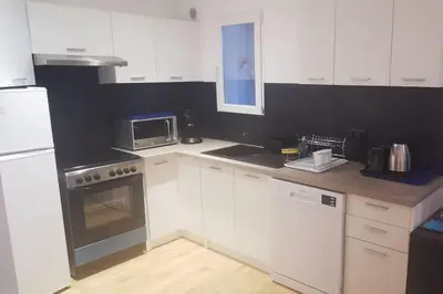 a kitchen with white cabinets and a stove and a microwave at Pieds dans l'eau - La Villa Crique aux tortues in Zonza