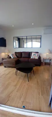 a living room with a brown couch in a room at Pieds dans l'eau - La Villa Crique aux tortues in Zonza
