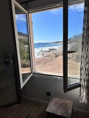 a room with two windows and a view of the ocean at Casa Mare, CABANON SUR LA PLAGE à Ajaccio vue sanguinaires in Ajaccio