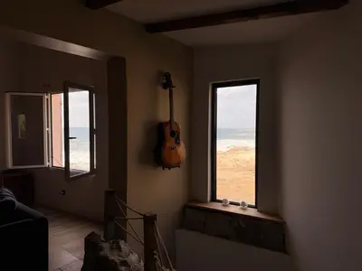 a room with a guitar on the wall next to a window at Casa Mare, CABANON SUR LA PLAGE à Ajaccio vue sanguinaires in Ajaccio