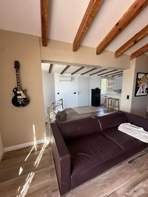 a living room with a couch and a guitar on the wall at Casa Mare, CABANON SUR LA PLAGE à Ajaccio vue sanguinaires in Ajaccio