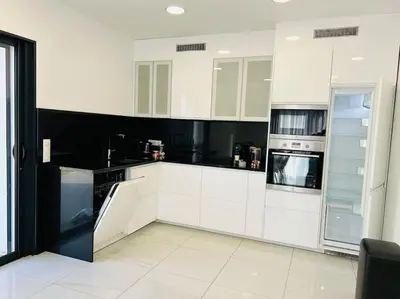 a white kitchen with black and white appliances at Villa Climatisée avec Piscine partagée , Terrasse et Parking in Prunelli-di-Fiumorbo