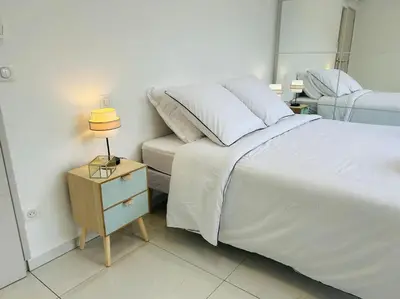 a bedroom with a bed and a night stand with a lamp at Villa Climatisée avec Piscine partagée , Terrasse et Parking in Prunelli-di-Fiumorbo