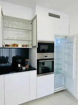 a white kitchen with white cabinets and appliances at Villa Climatisée avec Piscine partagée , Terrasse et Parking in Prunelli-di-Fiumorbo