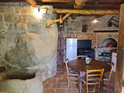a kitchen with a wooden table and a stone wall at BERGERIE DE 1770 AVEC PISCINE in Sartène