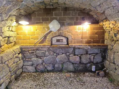 a stone wall with a brick oven with a shovel at BERGERIE DE 1770 AVEC PISCINE in Sartène