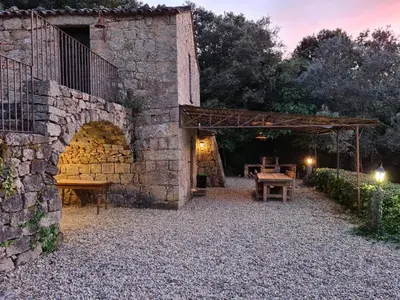 a stone building with a table and a stone wall at BERGERIE DE 1770 AVEC PISCINE in Sartène