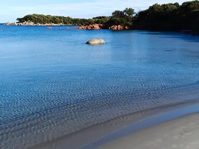 a beach with a large rock in the water at T3 Picchiarini, Clim, piscines, resto, 5' plages in Lecci