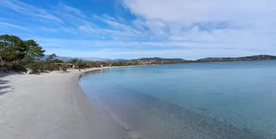 a beach with blue water and mountains in the background at T3 Picchiarini, Clim, piscines, resto, 5' plages in Lecci