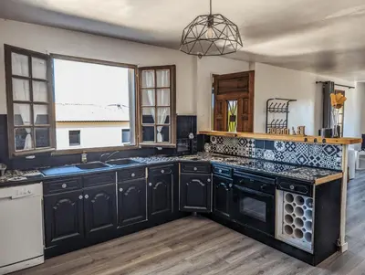 a kitchen with black cabinets and a large window at I Tre Taglincchi, U Sicondu - Proche mer, Clim, Wifi, Parking gratuit in Taglio-Isolaccio