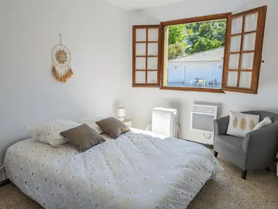 a bedroom with a bed and a chair and a window at I Tre Taglincchi, U Sicondu - Proche mer, Clim, Wifi, Parking gratuit in Taglio-Isolaccio