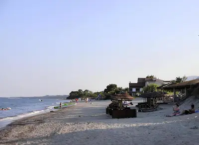 a beach with people sitting on the sand and the ocean at I Tre Taglincchi, U Terzu - Proche mer, Clim, Wifi, Parking gratuit in Taglio-Isolaccio