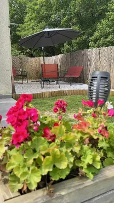 a garden with red flowers and two benches and an umbrella at I Tre Taglincchi, U Terzu - Proche mer, Clim, Wifi, Parking gratuit in Taglio-Isolaccio