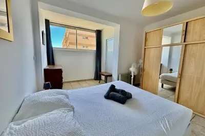 a bedroom with a white bed and a large window at Grand T3 avec vue mer - Proche plage - Parking & AC in Ajaccio