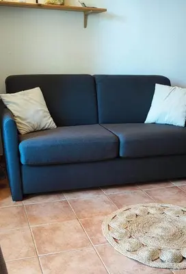 a blue couch with two pillows on it in a room at appartement bord de mer en Corse avec 2 piscines 100 metres de la plage in Linguizzetta