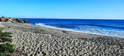 a sandy beach with the ocean in the background at appartement bord de mer en Corse avec 2 piscines 100 metres de la plage in Linguizzetta