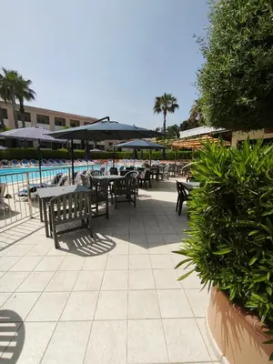 a patio with tables and umbrellas next to a pool at appartement bord de mer en Corse avec 2 piscines 100 metres de la plage in Linguizzetta