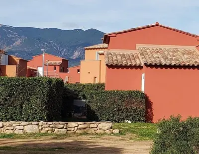 a red house with a stone wall in front at T3 Madiana, Climatisé, piscines, resto, 5mn plages in Lecci