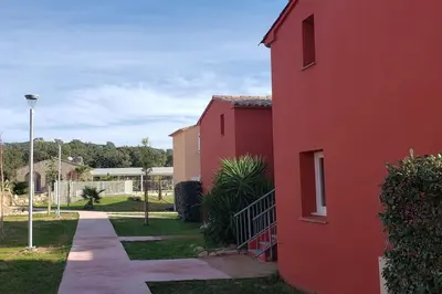 a red building with a sidewalk next to a street at T3 Madiana, Climatisé, piscines, resto, 5mn plages in Lecci