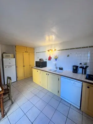 a kitchen with yellow cabinets and a white counter top at Maison de village calme et agréable in Albitreccia