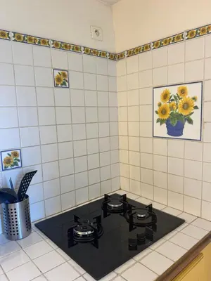 a black stove top in a white tiled kitchen at Maison de village calme et agréable in Albitreccia