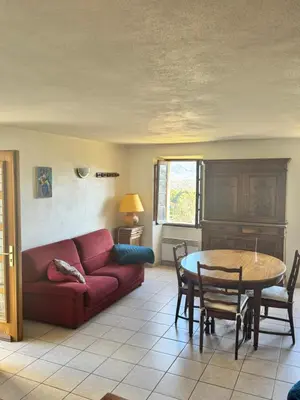 a living room with a red couch and a table at Maison de village calme et agréable in Albitreccia