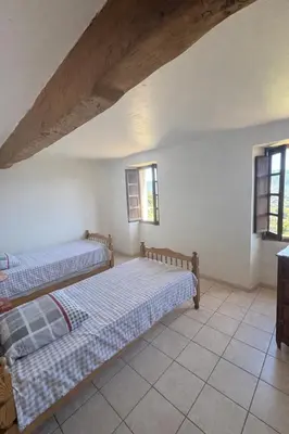 two beds in a room with two windows at Maison de village calme et agréable in Albitreccia